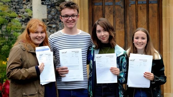 Vier Schüler der Thetford Grammar School stehen draußen und zeigen stolz ihre Zeugnisse.