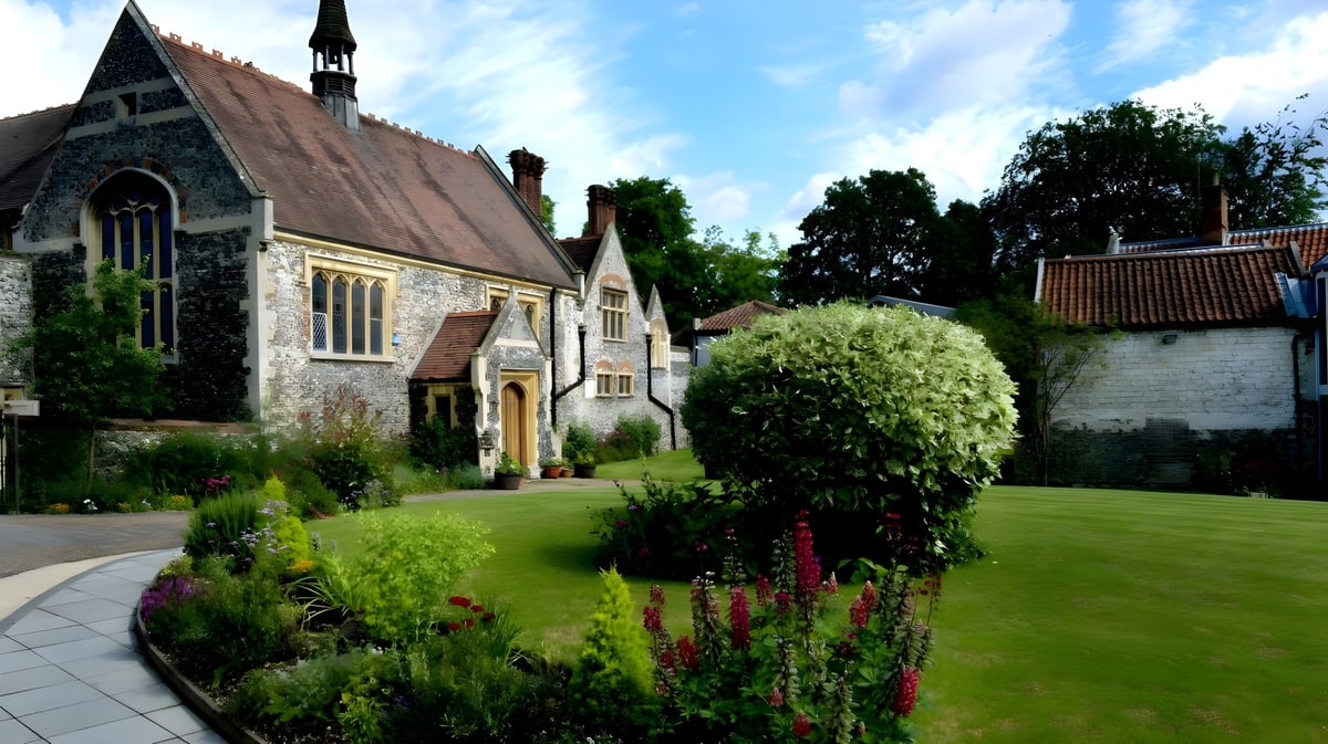 Die Steinkirche mit blühendem Garten und Rasenfläche auf dem Campus der Thetford Grammar School.