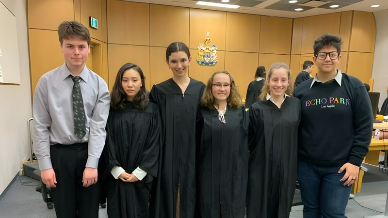 Schüler der Thornhill Secondary School stehen in formeller Kleidung vor einem Wappen.