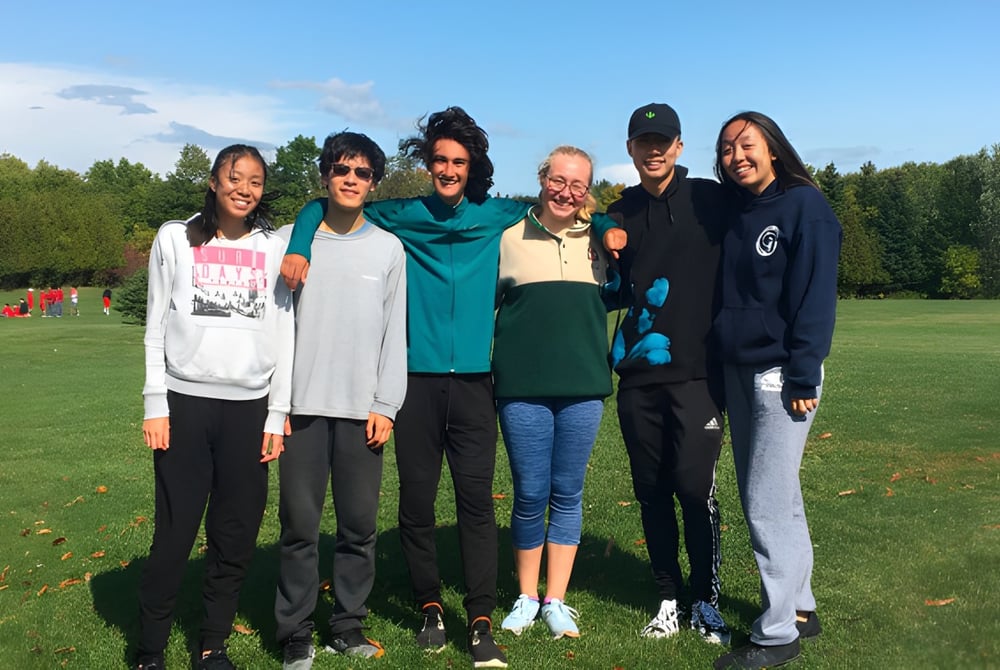 Eine Gruppe von Schülerinnen und Schülern steht auf einer Wiese mit Bäumen im Hintergrund auf dem Gelände der Thornlea Secondary School.