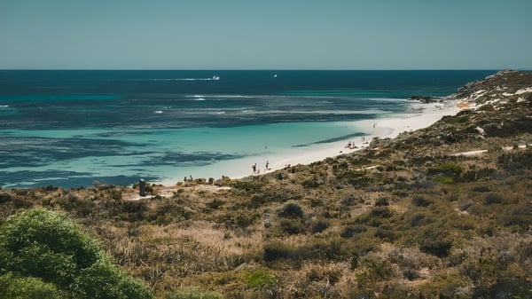 Küstenlandschaft mit Strand, türkisfarbenem Wasser und bewachsenem Hügel nahe der Thornlie Senior High School.