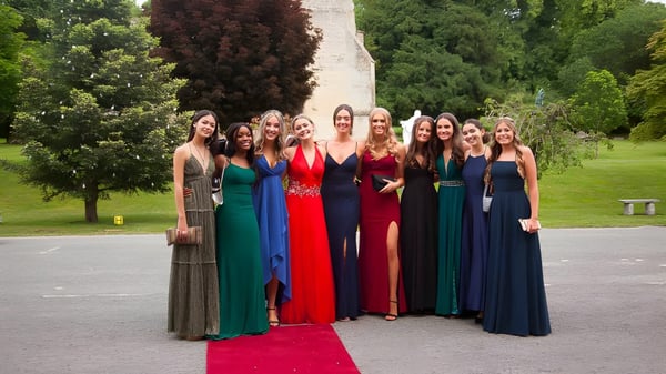 Eine Gruppe junger Frauen in Abendkleidern steht gemeinsam im Park auf dem Campus des Thornton College.