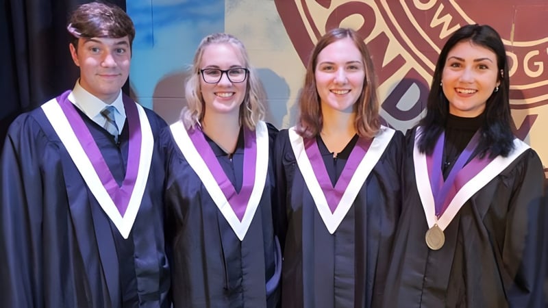 Vier Schülerinnen und Schüler der Thousand Islands Secondary School stehen in Abschlusskleidung vor einem farbigen Hintergrund mit Universitätslogo.