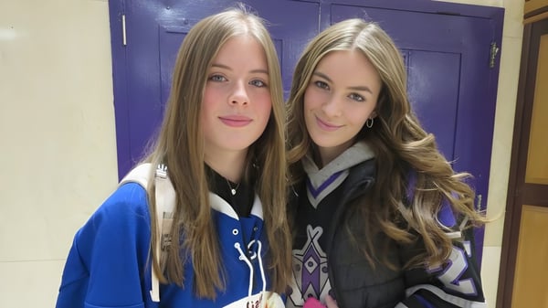 Zwei Schülerinnen der Thousand Islands Secondary School stehen vor einer lila Tür und lächeln in die Kamera.