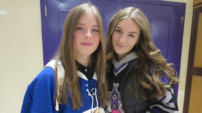 Zwei Schülerinnen der Thousand Islands Secondary School stehen vor einer lila Tür und lächeln in die Kamera.