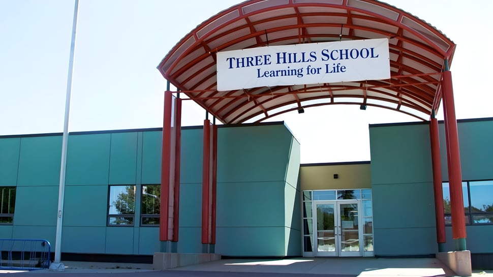 Der Eingang der Three Hills School mit rotem Ziegeldach und einem Schild mit dem Motto Learning for Life.