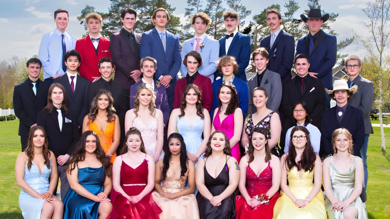 Schülerinnen und Schüler der Three Hills School stehen in formeller Kleidung zusammen auf einer Wiese mit Bäumen im Hintergrund.