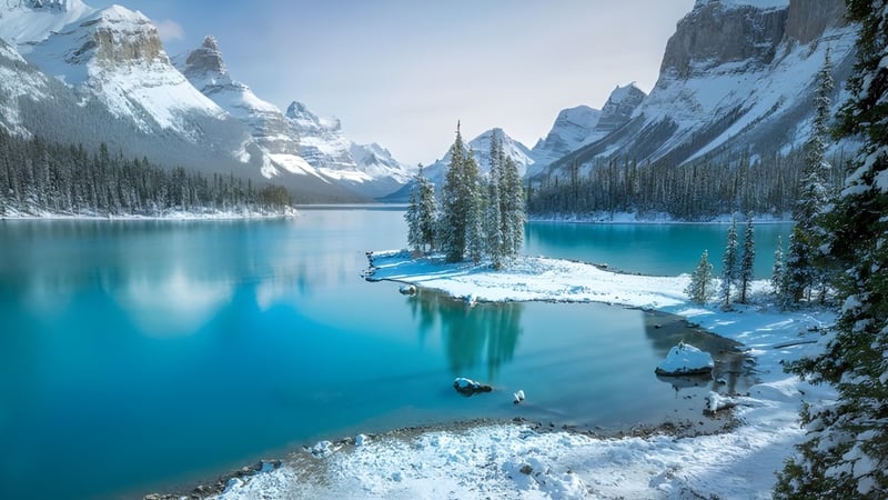 Verschneite Landschaft mit türkisfarbenem See und Waldinsel in den Bergen bei der Three Hills School.