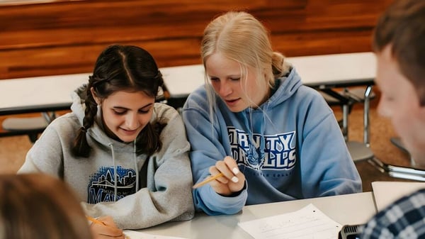 Zwei Schülerinnen der Three Rivers Christian School arbeiten gemeinsam an einem Schreibtisch mit Holzverkleidung im Hintergrund.