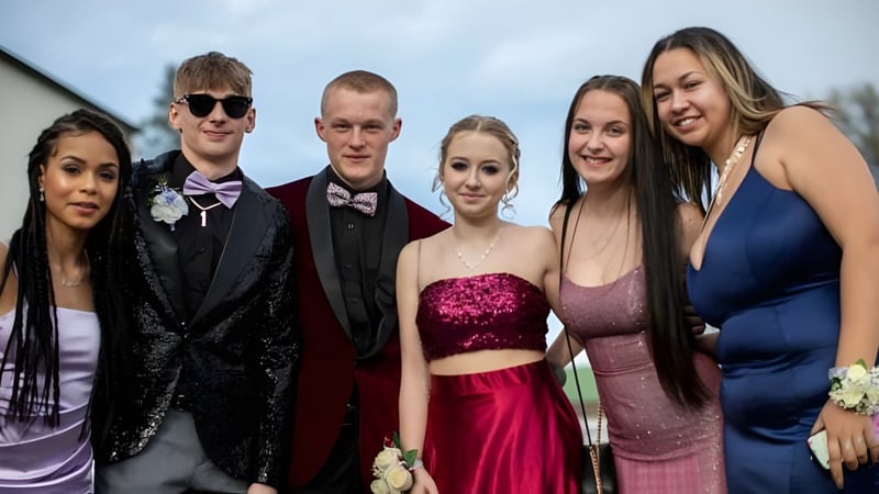 Eine Gruppe von gut gekleideten Personen posiert gemeinsam vor unscharfem Hintergrund auf dem Gelände der Three Rivers Christian School.