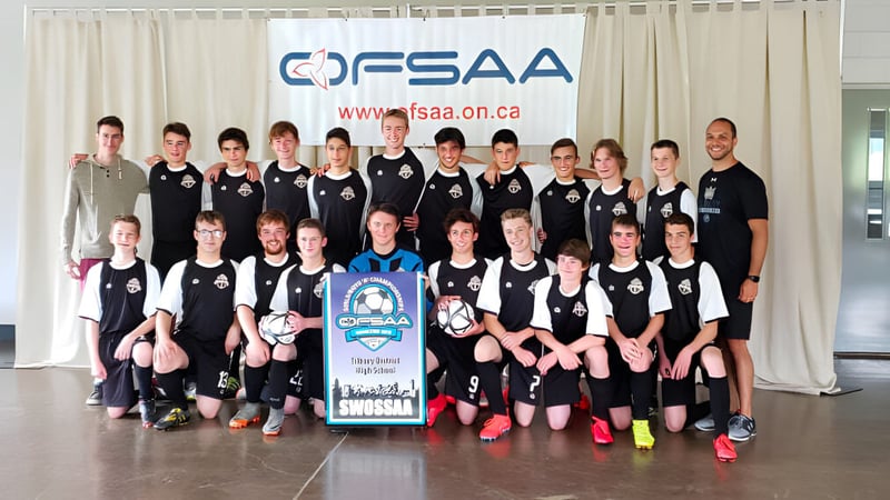 Eine Gruppe weiblicher Schüler der Tilbury District High School steht vor einem OFSAA-Banner.