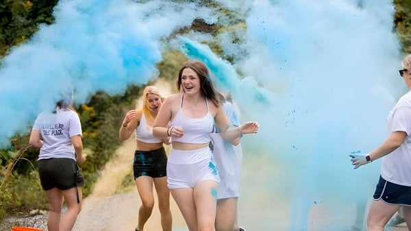 Eine Gruppe Schüler der Tilton School läuft im Freien durch eine Wolke aus lebendig blauem Rauch vor grünem Hintergrund.