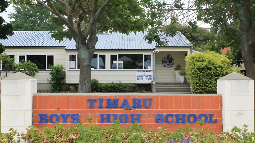 Das hölzerne Gebäude mit Metall-Dach auf dem Campus der Timaru Boys School ist von Bäumen umgeben.