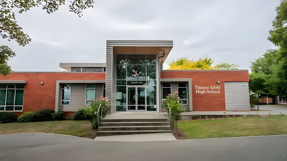 Das moderne Gebäude auf dem Campus der Timaru Girls School ist von Bäumen und einer Rasenfläche umgeben.