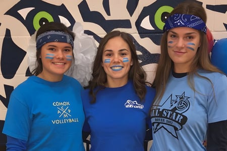 Drei Schülerinnen der Timberline Secondary School posieren vor einem bunten Graffiti-Hintergrund.