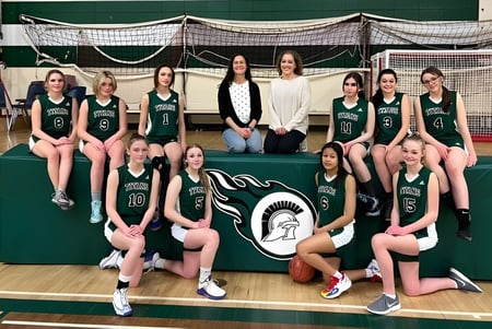 Eine Gruppe junger Basketballspielerinnen posiert gemeinsam auf dem Basketballplatz der Tofield School.