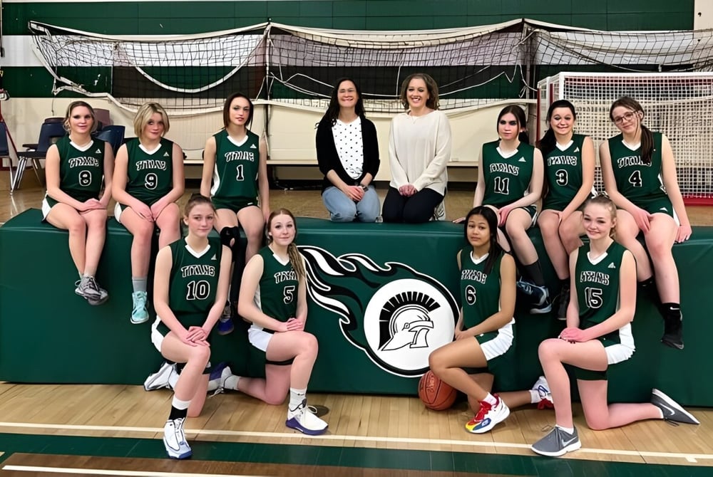 Eine Gruppe junger Basketballspielerinnen posiert gemeinsam auf dem Basketballplatz der Tofield School.