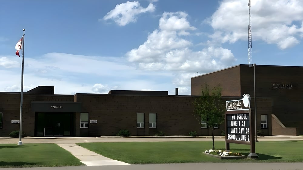 Das Backsteingebäude der Tofield School mit einer kanadischen Flagge und einer Grünfläche im Vordergrund.