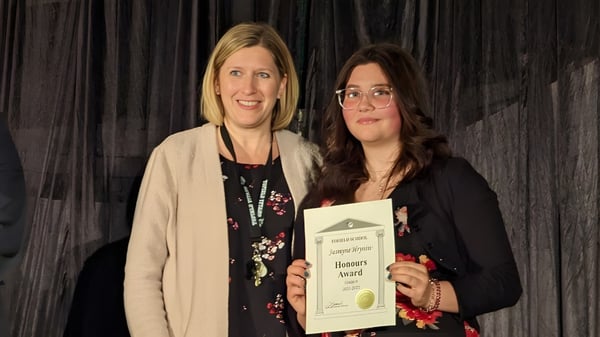 Zwei Frauen stehen zusammen und halten ein Zertifikat auf dem Campus der Tofield School.