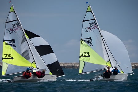 Zwei Segelboote mit britischer Flagge segeln bei blauem Himmel auf dem Wasser nahe der Tonbridge School.