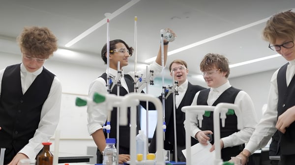 Eine Gruppe Schüler der Tonbridge School steht in einem Raum mit wissenschaftlichen Geräten und Instrumenten im Hintergrund.