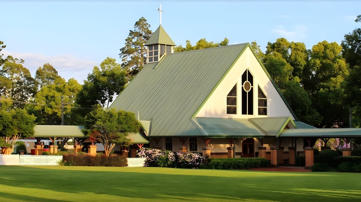 Eine Kirche mit spitzem Dach steht in einer grünen Landschaft auf dem Gelände der Toowoomba Anglican School.
