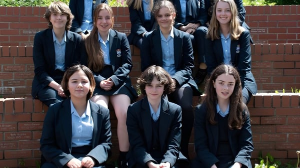 Eine Gruppe Schülerinnen der Torquay Girls Grammar School steht gemeinsam vor einer Ziegelwand.