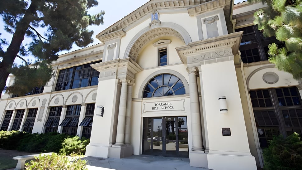 Das geschwungene historische Gebäude der Torrance High School ist von Bäumen umgeben.