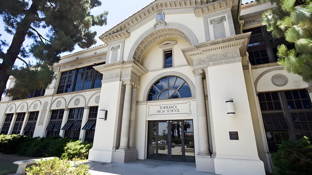 Das geschwungene historische Gebäude der Torrance High School ist von Bäumen umgeben.