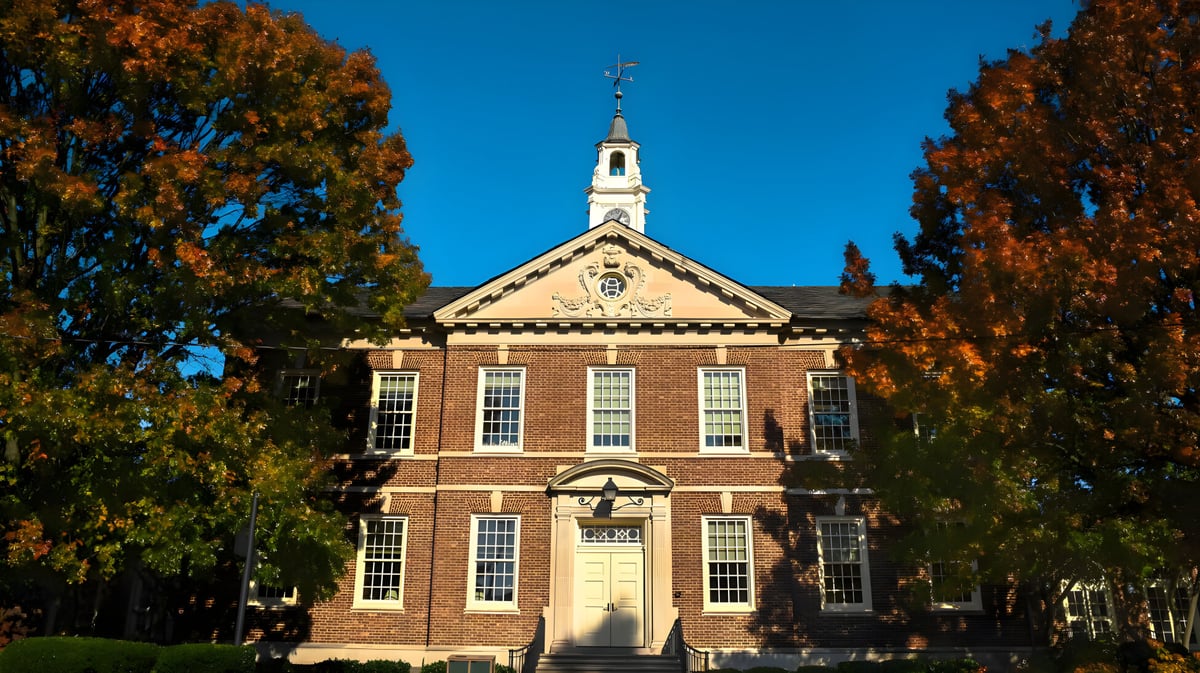 Das Backsteingebäude mit dem markanten Uhrenturm auf dem Campus der Tower Hill School ist von herbstlichem Laub umgeben.