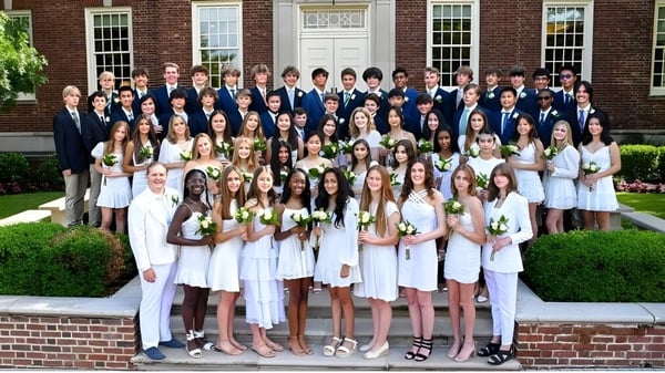 Eine Gruppe von Schülerinnen und Schülern der Tower Hill School steht gemeinsam vor einem Backsteingebäude mit Säulen.