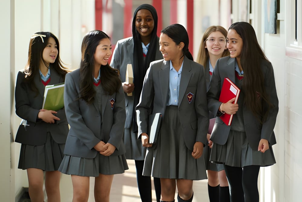 Schülerinnen und Schüler der Townley Grammar School gehen gemeinsam durch einen Flur mit roten Wänden.