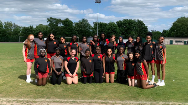 Eine Gruppe Schüler des Townley Grammar School posiert gemeinsam auf einem Sportfeld mit Stadion im Hintergrund.