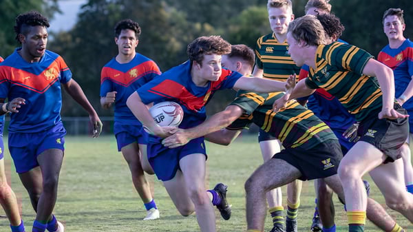 Schüler der Townsville Grammar School spielen ein intensives Rugbyspiel auf einem grünen Spielfeld.