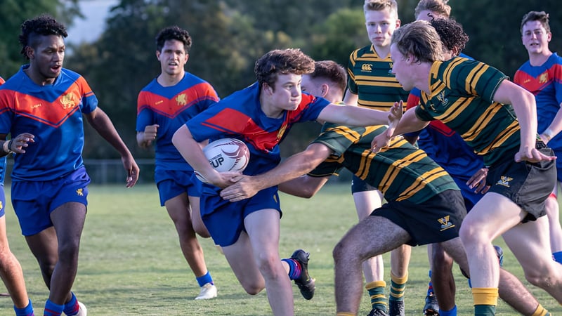 Schüler der Townsville Grammar School spielen ein intensives Rugbyspiel auf einem grünen Spielfeld.