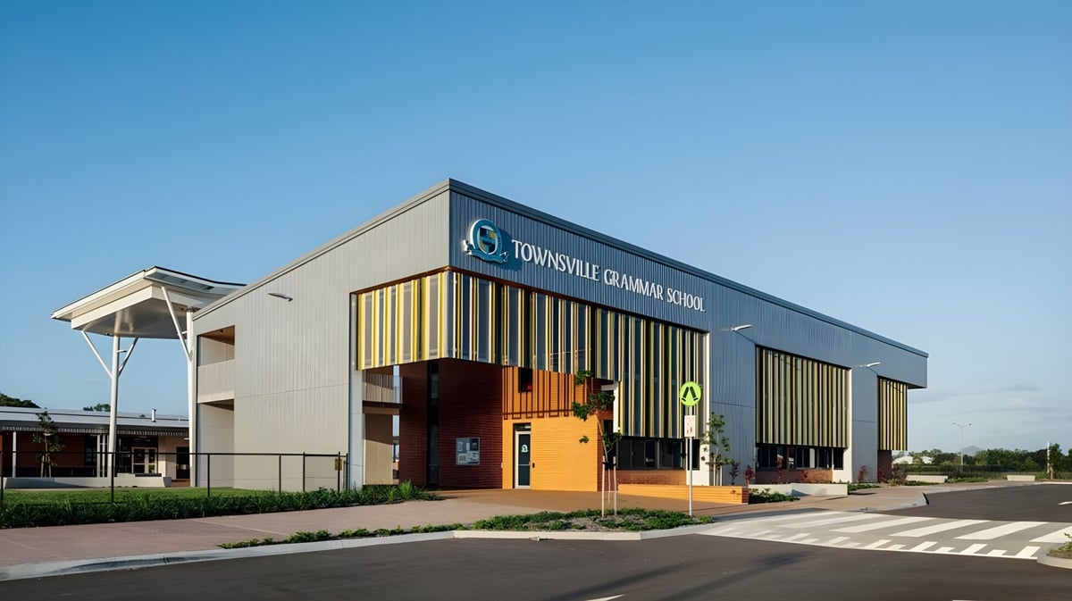 Das moderne Schulgebäude der Townsville Grammar School mit großem Logo und Parkplatz im Vordergrund bei klarem Himmel.