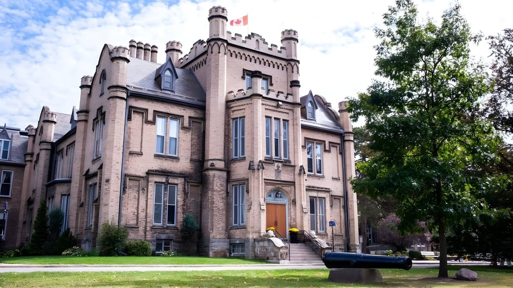 Das historische Backsteingebäude mit Türmen der Trafalgar Castle School steht in einem von Bäumen gesäumten Hof mit einer Kanone im Vordergrund.