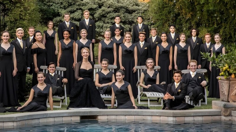Eine Gruppe von Schülerinnen und Schülern der Trafalgar Castle School steht in formeller schwarzer Kleidung an einem Pool im Freien mit grüner Umgebung.