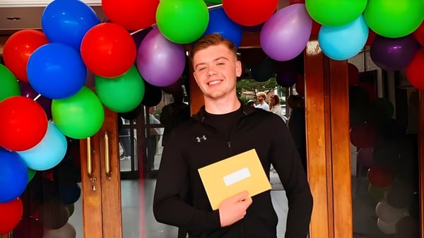 Eine Person in schwarzem Shirt steht vor einem bunten Ballon-Display auf dem Campus der Trafalgar School.