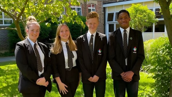 Vier Schülerinnen und Schüler in Schuluniformen stehen zusammen auf dem Campus der Trafalgar School im Freien.