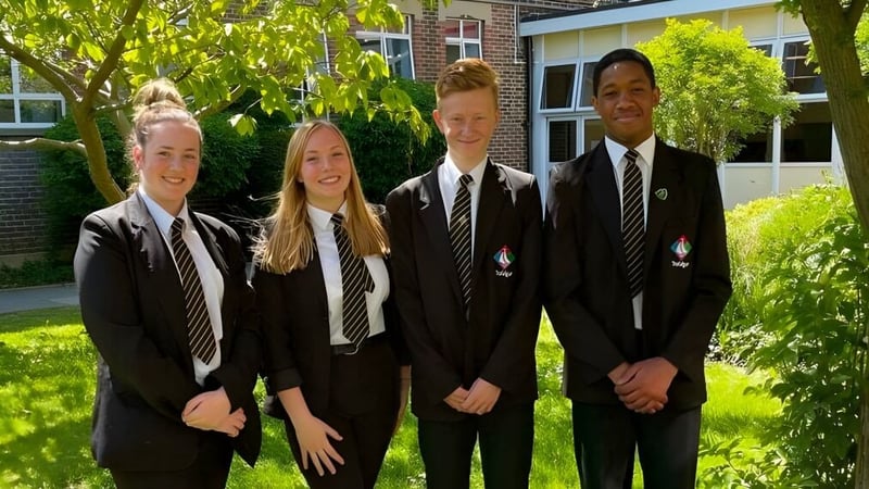 Vier Schülerinnen und Schüler in Schuluniformen stehen zusammen auf dem Campus der Trafalgar School im Freien.