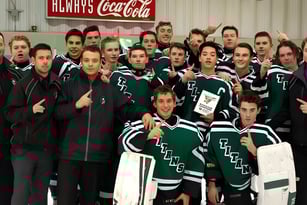 Eine Gruppe Schülerinnen und Schüler in grünen und weißen Sportuniformen posiert vor einem roten Coca-Cola Schild auf dem Gelände der Transcona Collegiate.