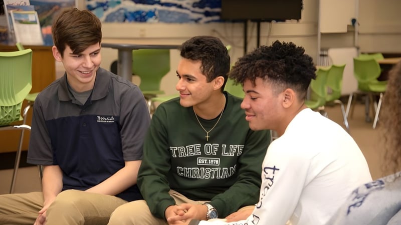 Drei Schüler sitzen in einem Klassenraum der Tree of Life Christian School und führen ein Gespräch.