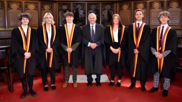 Eine Gruppe von Personen in akademischen Talaren steht bei einer Graduationsfeier auf dem Campus des Trent College.