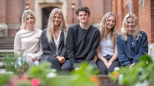 Fünf Schüler sitzen auf einer Treppe vor Ziegelgebäuden auf dem Campus des Trent College.