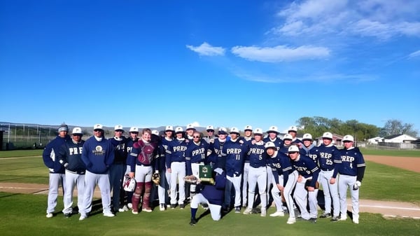 Eine Gruppe von Baseballspielern steht auf dem Spielfeld der Tri-Cities Prep Catholic High School unter klarem Himmel.