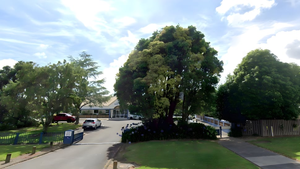 Ein gepflasterter Weg führt durch grüne Bäume zu einem Haus auf dem Gelände der Trident High School.