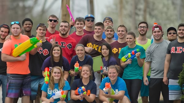 Studierende der Trine University nehmen an einem spielerischen Wasserkampf im Freien teil.