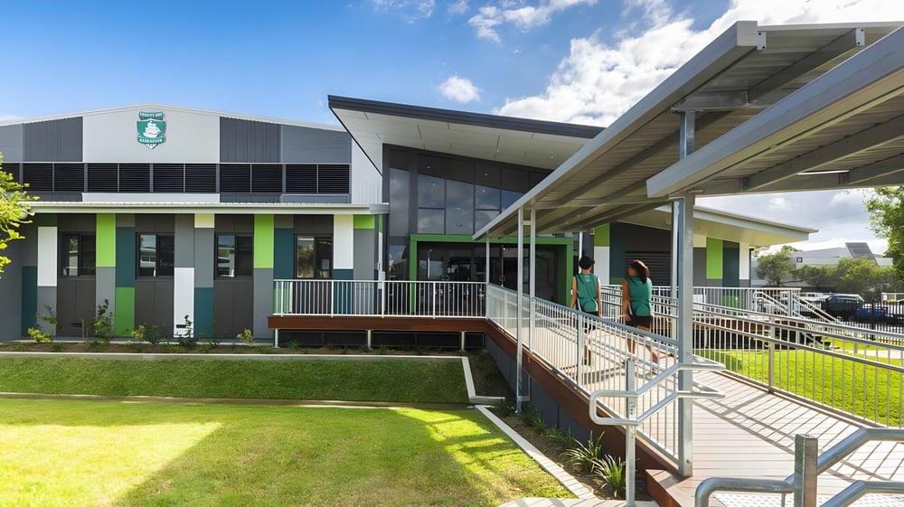 Das moderne mehrstöckige Gebäude der Trinity Bay State High School ist von einer Wiese und einem Weg mit Geländern umgeben.