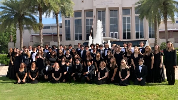Eine Gruppe Schüler der Trinity Catholic High School steht in formeller schwarzer Kleidung vor einem Gebäude mit Palmen.
